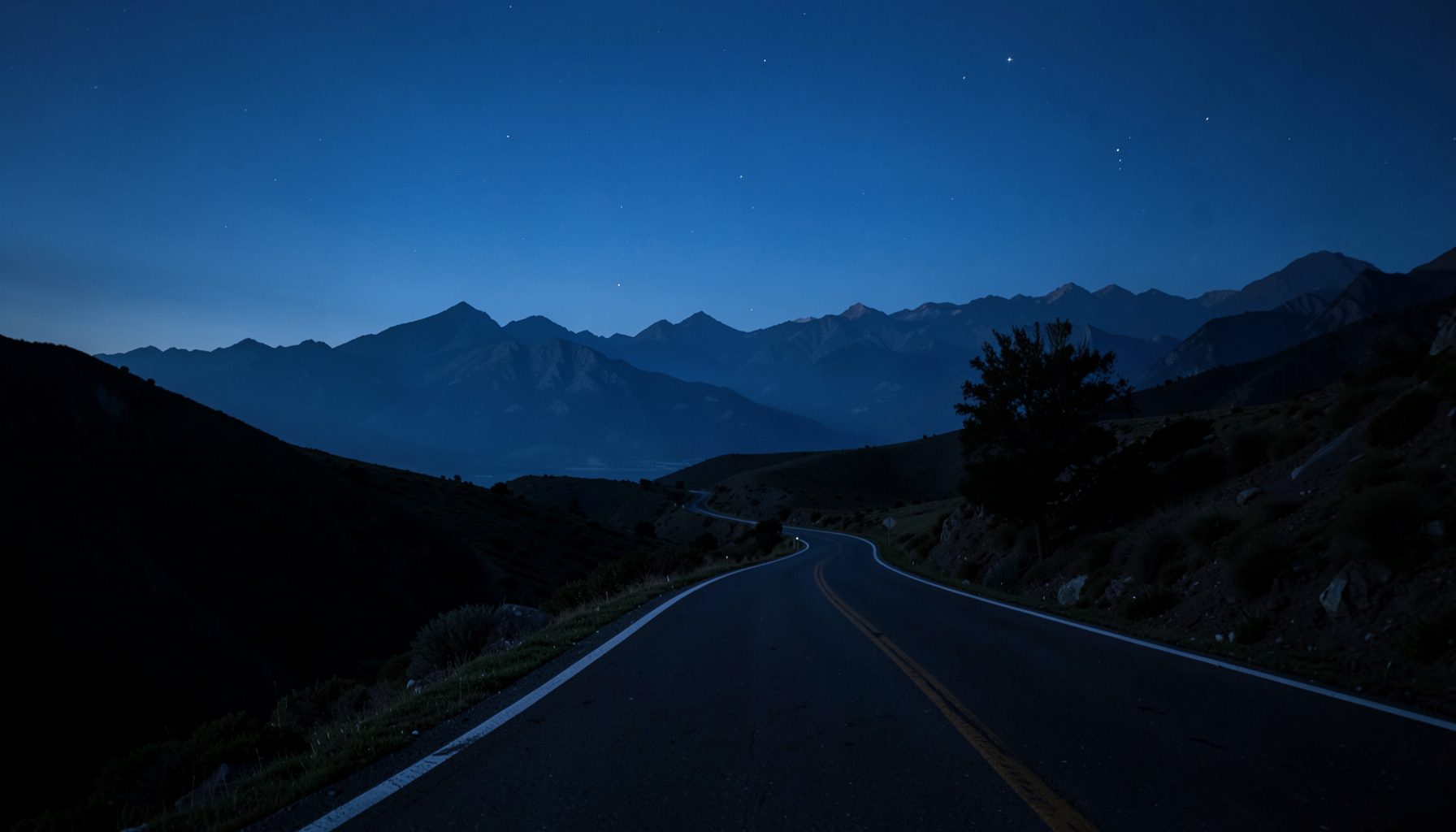 Paisagem noturna atmosférica com uma estrada sinuosa estendendo-se em direção a montanhas distantes sob um céu azul-petróleo, clima sereno e contemplativo