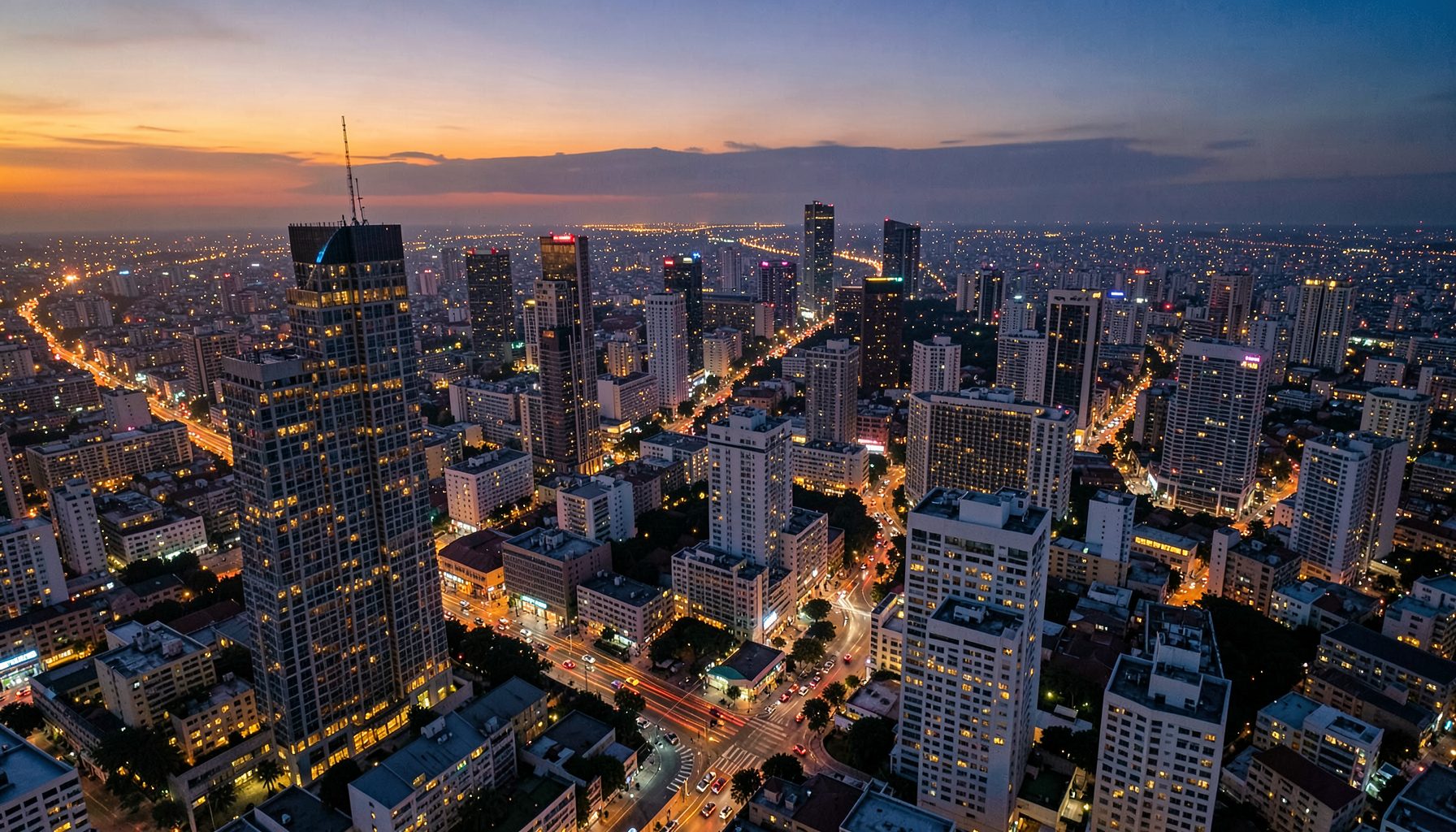 Vista aérea de uma cidade iluminada ao entardecer com arranha-céus e hotéis, tons quentes de dourado e azul-escuro